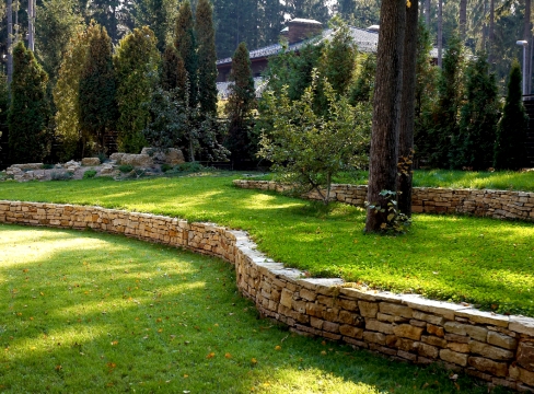 Muro de contención de bricolaje en un jardín de piedra, hormigón y madera